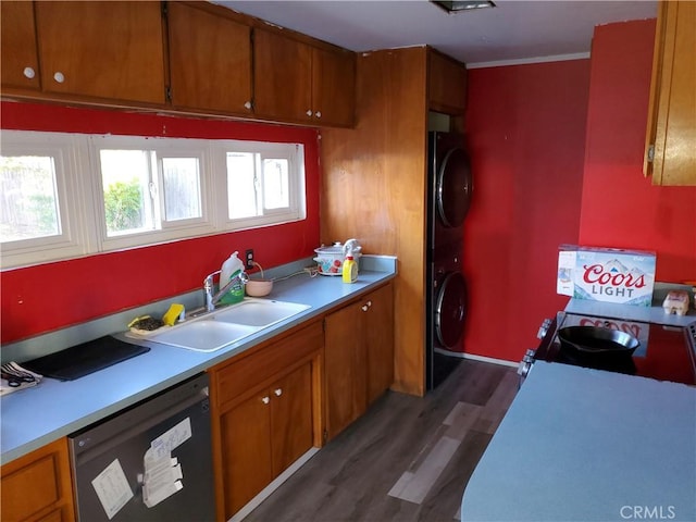 kitchen with sink, dark hardwood / wood-style floors, ornamental molding, appliances with stainless steel finishes, and stacked washer / dryer