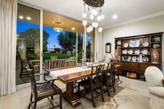 dining room featuring light wood-type flooring, an inviting chandelier, and crown molding