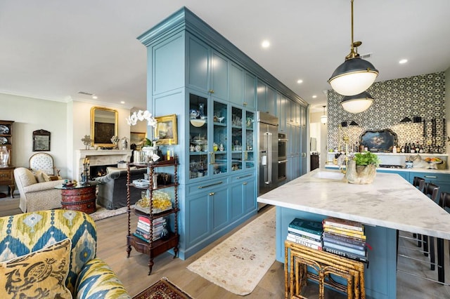 kitchen featuring tasteful backsplash, blue cabinets, crown molding, light hardwood / wood-style flooring, and hanging light fixtures