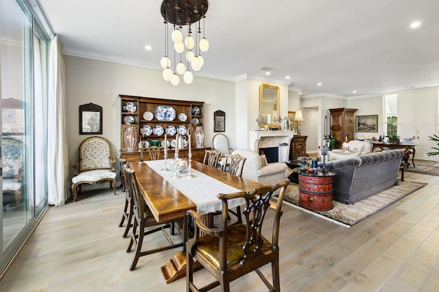 dining area featuring a notable chandelier, a healthy amount of sunlight, ornamental molding, and light hardwood / wood-style flooring