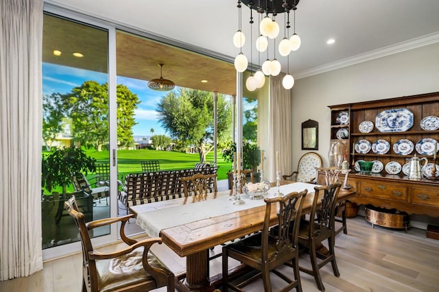 dining room featuring a notable chandelier, light hardwood / wood-style floors, a wall of windows, and crown molding