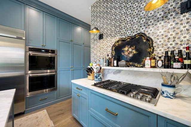 kitchen with blue cabinetry, appliances with stainless steel finishes, and backsplash