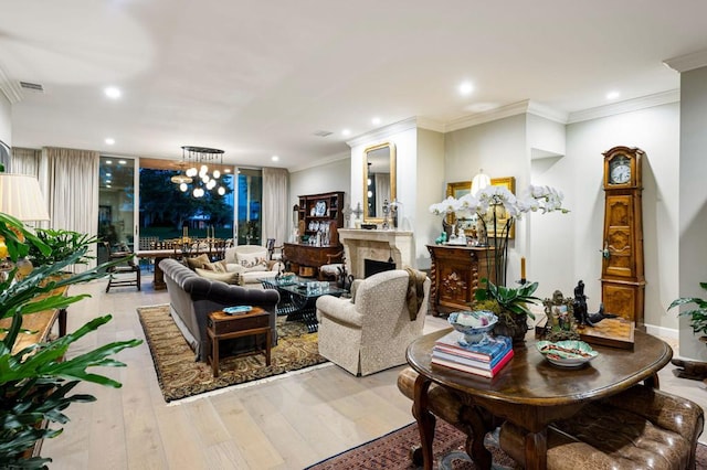 living room with light wood-type flooring, ornamental molding, and an inviting chandelier