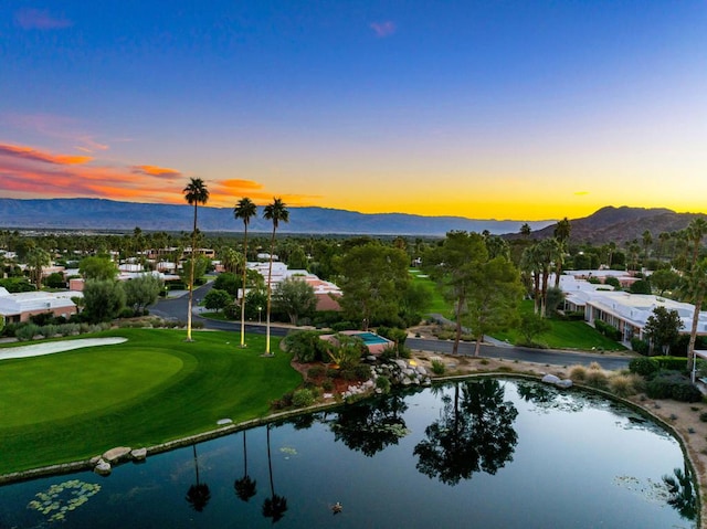 aerial view at dusk featuring a water and mountain view