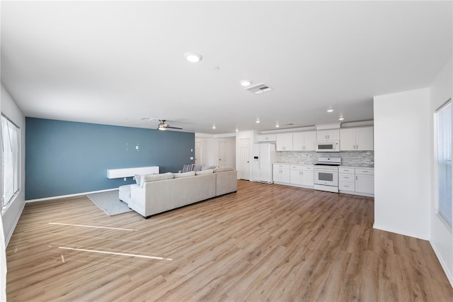 unfurnished living room with plenty of natural light, ceiling fan, and light hardwood / wood-style flooring