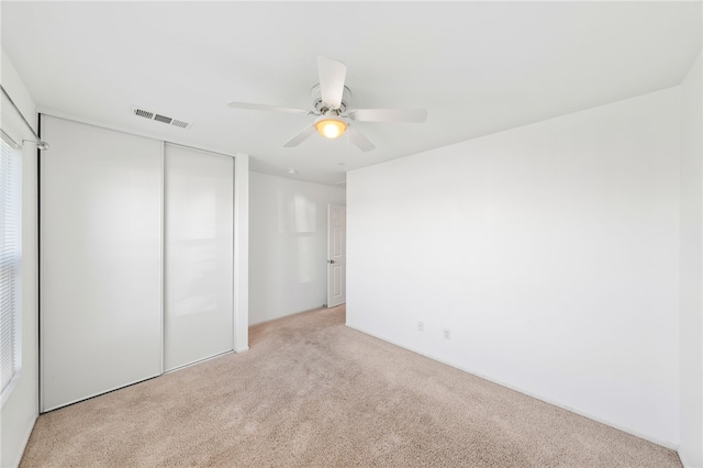 unfurnished bedroom with light carpet, a closet, and ceiling fan