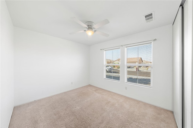 empty room featuring ceiling fan and light colored carpet