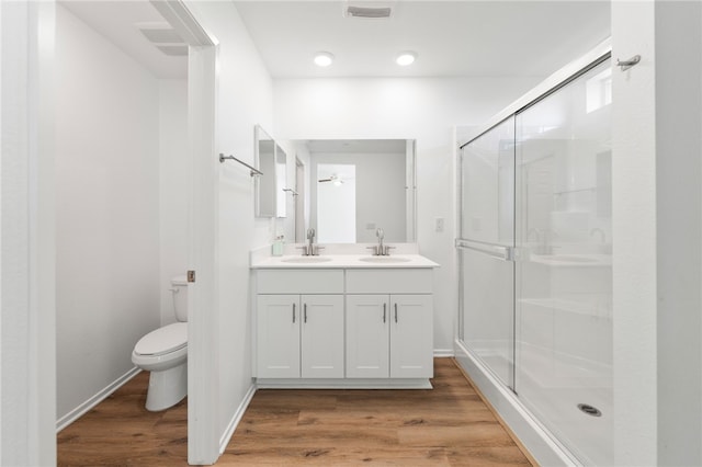 bathroom with hardwood / wood-style flooring, vanity, toilet, and walk in shower