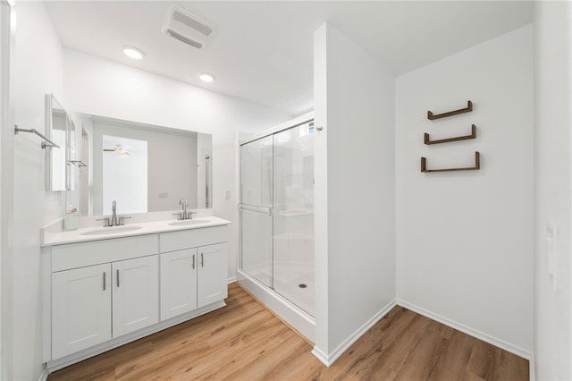 bathroom with ceiling fan, a shower with door, and hardwood / wood-style flooring