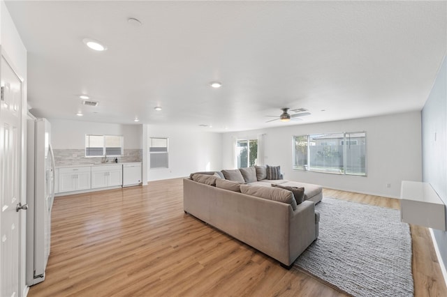 living room with ceiling fan, light hardwood / wood-style flooring, and sink