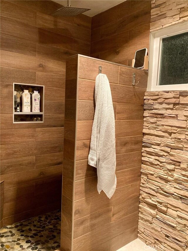 bathroom featuring wood walls and walk in shower