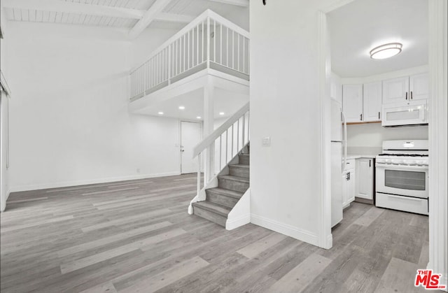 stairs featuring beamed ceiling, a towering ceiling, and hardwood / wood-style flooring