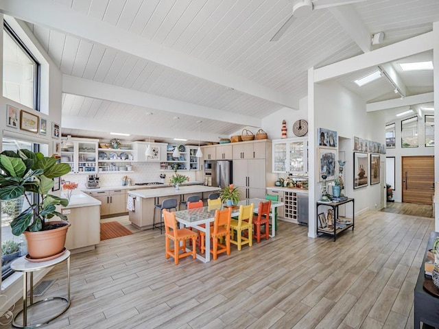 dining area with high vaulted ceiling, beam ceiling, and light hardwood / wood-style floors