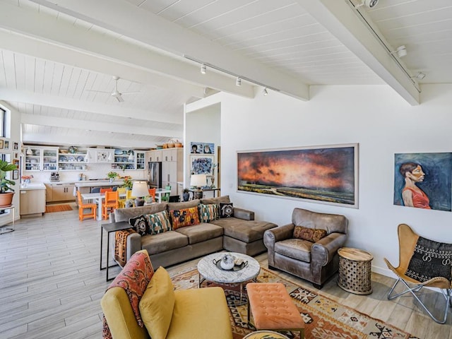 living room with light hardwood / wood-style flooring, vaulted ceiling with beams, and track lighting