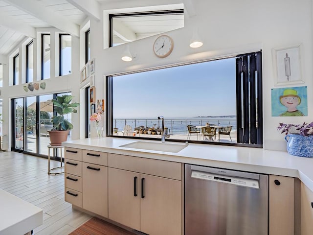 kitchen featuring dishwasher, sink, light hardwood / wood-style floors, a water view, and beam ceiling