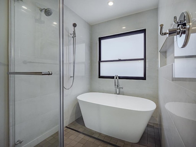 bathroom featuring tile patterned flooring, plus walk in shower, and tile walls