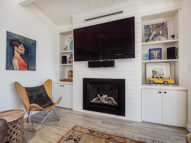 interior space with built in shelves, wood ceiling, lofted ceiling with beams, light hardwood / wood-style flooring, and a fireplace