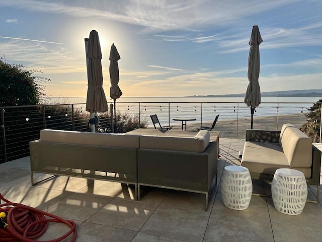 patio terrace at dusk with an outdoor living space and a water view