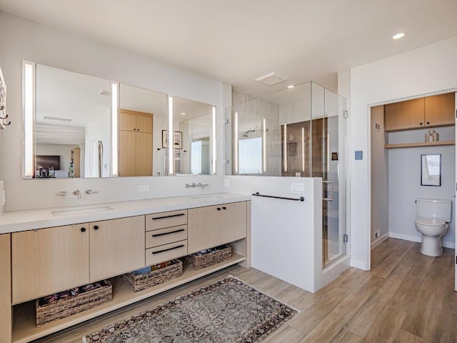 bathroom with hardwood / wood-style flooring, vanity, an enclosed shower, and toilet