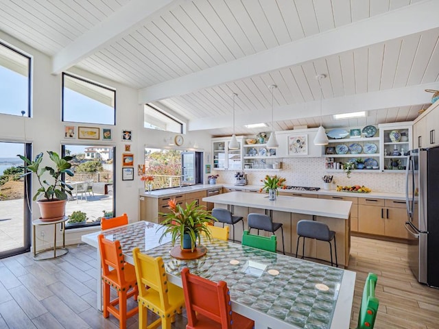 dining space featuring vaulted ceiling with beams and light hardwood / wood-style flooring