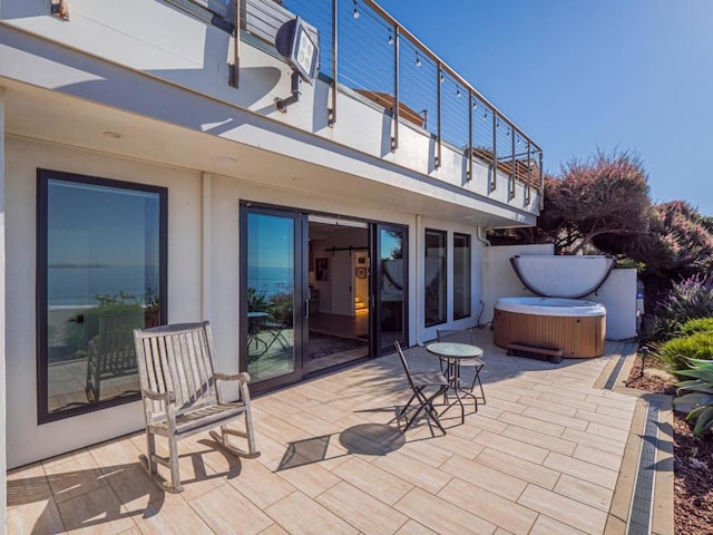 view of patio / terrace with a balcony and a hot tub