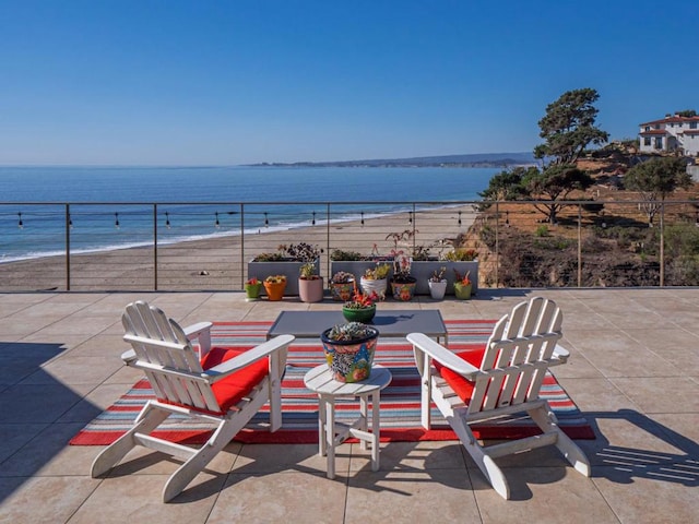 view of patio with a water view and a beach view