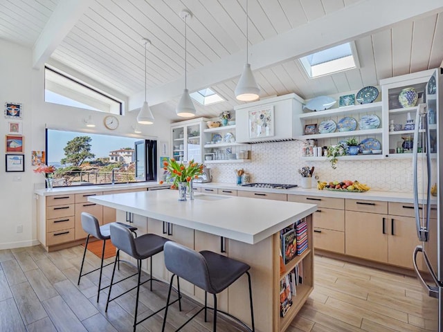 kitchen featuring lofted ceiling with skylight, a kitchen island, stainless steel fridge, backsplash, and a kitchen breakfast bar