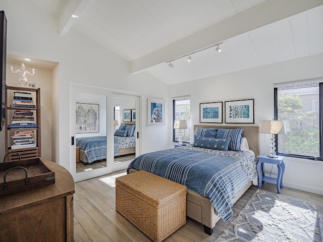 bedroom featuring lofted ceiling with beams, multiple windows, and light hardwood / wood-style floors