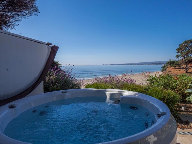 view of pool featuring a hot tub and a water view