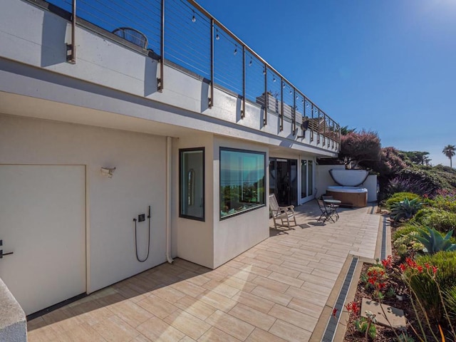 view of patio / terrace with a hot tub and a balcony