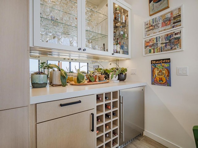 bar with high end refrigerator and light hardwood / wood-style floors