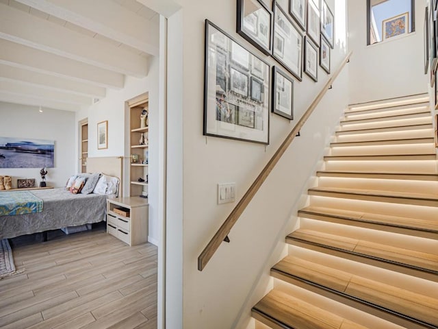 staircase featuring beamed ceiling and hardwood / wood-style floors