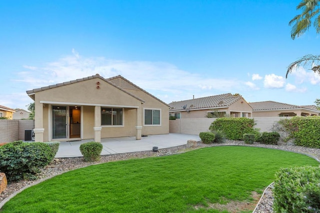 rear view of property with cooling unit, a yard, and a patio