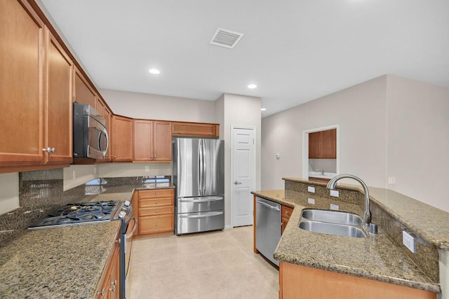 kitchen with tasteful backsplash, a center island with sink, sink, light stone countertops, and appliances with stainless steel finishes