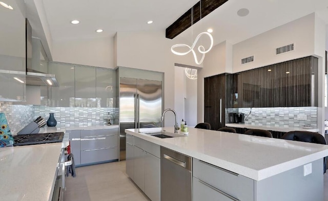 kitchen with decorative backsplash, beam ceiling, high quality appliances, and sink