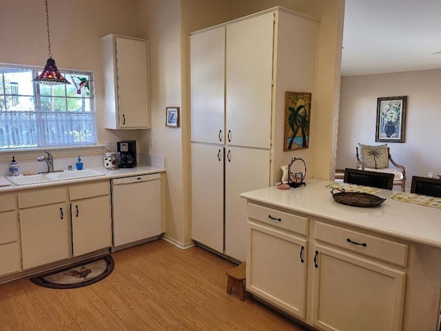 kitchen with dishwasher, sink, decorative light fixtures, and light hardwood / wood-style flooring