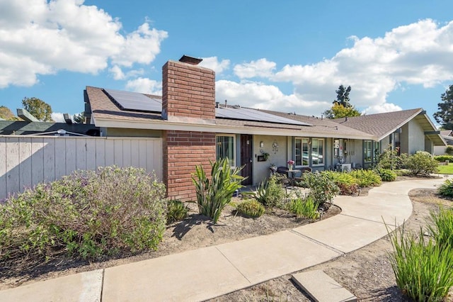 single story home featuring solar panels and a porch