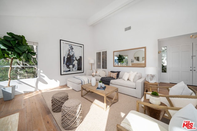 living room featuring beam ceiling, high vaulted ceiling, and light wood-type flooring