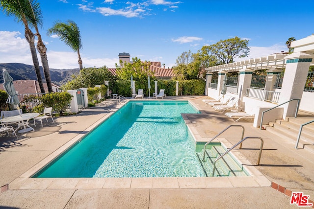 view of pool featuring a mountain view, a pergola, and a patio area