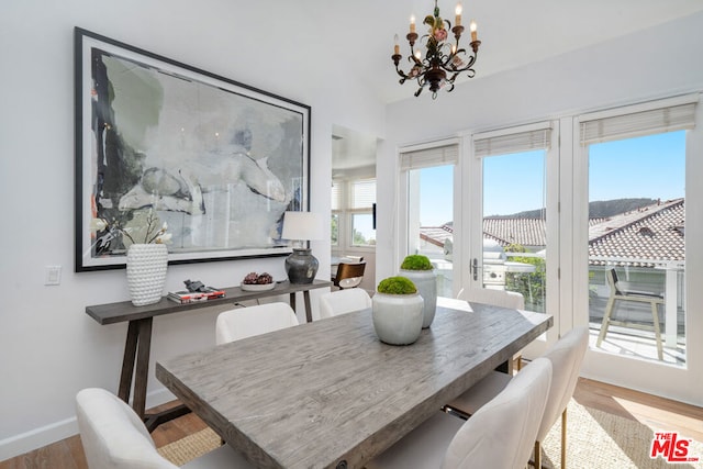 dining room with plenty of natural light, an inviting chandelier, lofted ceiling, and light hardwood / wood-style flooring