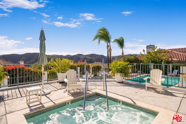 view of pool featuring a patio area, a mountain view, and a community hot tub