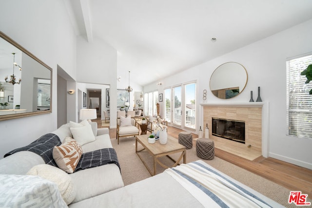 living room featuring a tile fireplace, light hardwood / wood-style flooring, beamed ceiling, and high vaulted ceiling