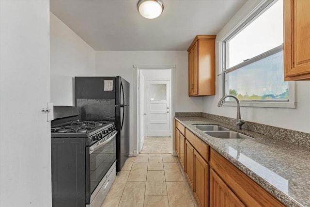 kitchen with light tile patterned floors, sink, a healthy amount of sunlight, and stainless steel range with gas stovetop