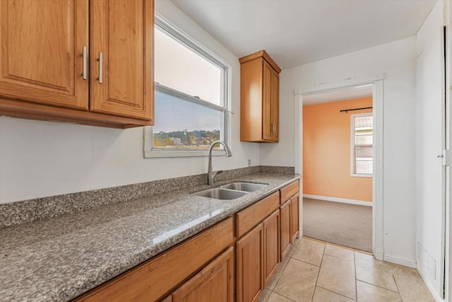 kitchen with light tile patterned floors, stone countertops, and sink