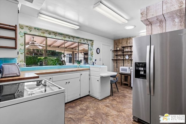 kitchen featuring white cabinetry, ceiling fan, stainless steel fridge with ice dispenser, kitchen peninsula, and range