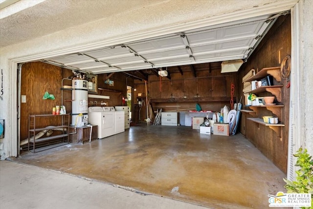 garage with secured water heater, wood walls, and washing machine and dryer