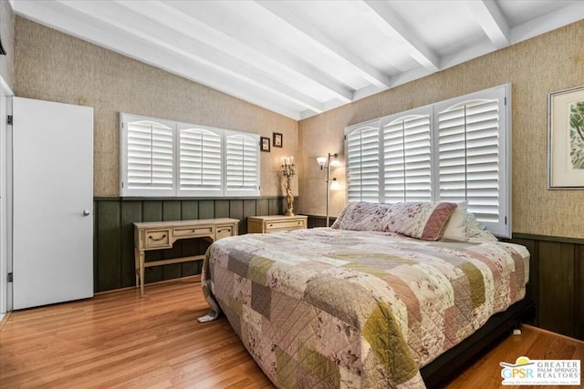 bedroom featuring beam ceiling, light wood-type flooring, multiple windows, and wood walls