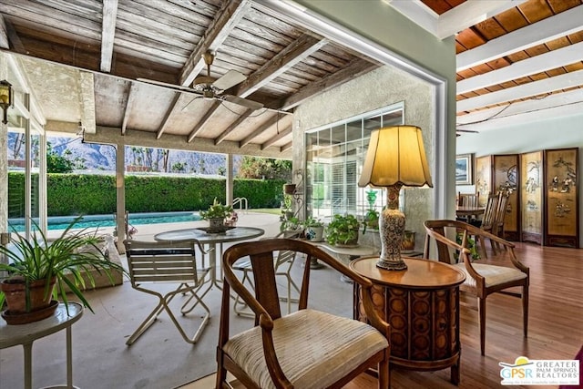 sunroom featuring beam ceiling, a pool, and wooden ceiling