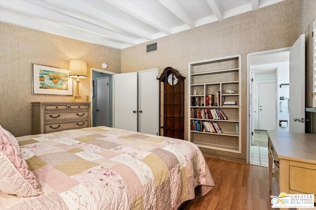 bedroom with beam ceiling and light hardwood / wood-style flooring