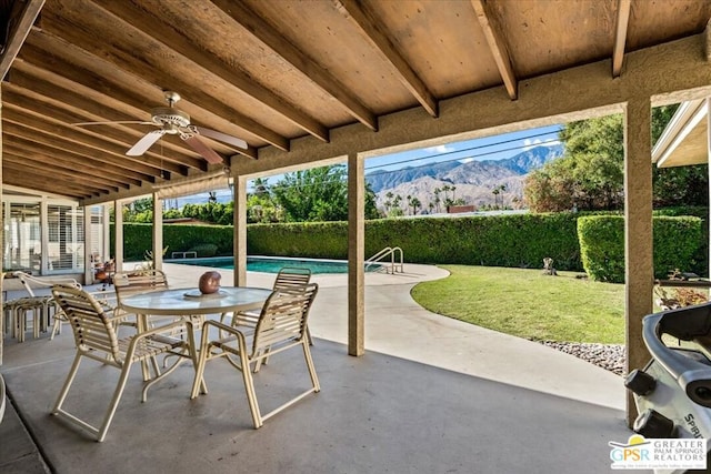 view of patio / terrace featuring a mountain view, ceiling fan, and a fenced in pool